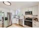 Well-lit kitchen featuring stainless steel appliances, white cabinets, and hardwood floors at 5563 Newland Way, Arvada, CO 80002