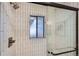 Modern shower with vertical white tiles, black trim, and clear glass sliding door at 5563 Newland Way, Arvada, CO 80002