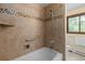 Tile bathroom featuring a shower-over-tub with decorative accents and a nearby window for natural light at 13609 Elsie Rd, Conifer, CO 80433