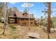 Back yard with multi-level deck and brown siding and roof, surrounded by lush trees at 13609 Elsie Rd, Conifer, CO 80433