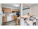 Functional kitchen with wood cabinetry, white appliances, and a breakfast bar for casual dining at 1008 N Corona St # 205, Denver, CO 80218