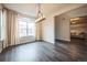 Sunlit dining area featuring wood floors, a modern chandelier, and an arched window with views of the neighborhood at 14221 Ivanhoe St, Thornton, CO 80602