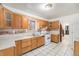 Eat-in kitchen boasts wooden cabinetry, tiled countertops, a gas range and tile flooring at 7 Elati St, Denver, CO 80223