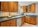 Well-lit kitchen featuring wood cabinets, tile backsplash, dishwasher, and a sink under a window at 2975 S Jackson St, Denver, CO 80210