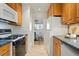 Galley kitchen featuring wood cabinets, stainless steel appliances, and a dining area at 2975 S Jackson St, Denver, CO 80210