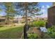 Lush backyard with fountain, black fence, mature trees and beautiful plantings and patio set nearby at 6917 E Girard Ave, Denver, CO 80224