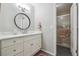 Bathroom with white vanity, framed round mirror, and walk-in shower with glass door at 6917 E Girard Ave, Denver, CO 80224
