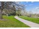 Curving paved pathway through a green space with sparse trees, and dandelions at 6917 E Girard Ave, Denver, CO 80224