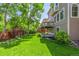 Well-manicured backyard with mature trees and partial view of a raised wooden deck at 9552 E Caley Cir, Englewood, CO 80111