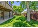 Expansive backyard with lush lawn, mature trees, and a deck overhead creating shaded space at 9552 E Caley Cir, Englewood, CO 80111