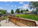 Relaxing backyard deck area with a wooden railing and view of the grassy yard and trees at 6508 S Garland Way, Littleton, CO 80123