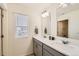 Bright bathroom featuring a double sink vanity with white countertop and grey cabinets, complemented by natural light from the window at 1005 Ryland Rd, Brighton, CO 80603