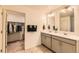 Bathroom with a double sink vanity, two mirrors, and a separate doorway to the walk-in closet at 1005 Ryland Rd, Brighton, CO 80603
