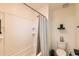 Clean bathroom features a white tiled shower/tub combo with a grey shower curtain, toilet, and modern shelf at 1005 Ryland Rd, Brighton, CO 80603
