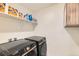 Functional laundry room with modern Samsung washer and dryer, complemented by upper shelf storage at 1005 Ryland Rd, Brighton, CO 80603