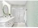 Clean bathroom featuring green patterned wallpaper, mirrored vanity, and glass shower at 950 Everett St, Lakewood, CO 80215