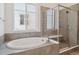 Luxurious bathroom featuring an oval soaking tub, tiled shower, and large window at 8250 Snake River St, Littleton, CO 80125