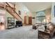 Cozy living room with vaulted ceiling, large windows, carpeted floors and a wooden staircase at 4858 S Queen St, Littleton, CO 80127