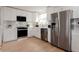 Well-lit kitchen with white cabinets, stainless steel appliances, and light wood flooring at 1390 S Jasmine Way, Denver, CO 80224