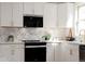 Modern kitchen with white cabinets, stainless steel appliances, and marble-style backsplash at 1390 S Jasmine Way, Denver, CO 80224