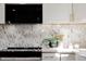 Close-up of a kitchen with white cabinets, black oven, and marble backsplash at 1390 S Jasmine Way, Denver, CO 80224
