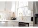 Bright kitchen with white cabinets, marble backsplash, and a stainless steel dishwasher at 1390 S Jasmine Way, Denver, CO 80224