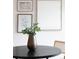 Close-up of a dark round table adorned with a vase and surrounded by stylish cane-backed chairs at 9369 Longs Peak Dr, Commerce City, CO 80640