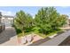 View of shared green space from condo balcony featuring trees and mailboxes at 9369 Longs Peak Dr, Commerce City, CO 80640