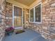Stone accented porch area with secure metal door covering and a welcoming front mat at 13990 E Chenango Dr, Aurora, CO 80015