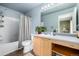Bright bathroom featuring a vanity with blond wood cabinets, neutral countertops, tub, and a large mirror at 3940 Malaya St, Denver, CO 80249