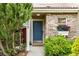 Charming home entrance featuring a blue front door, brick facade, and well-manicured greenery at 3940 Malaya St, Denver, CO 80249