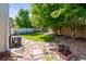 An outdoor view of a backyard space with mature trees, small lawn, stone tile, and wooden privacy fence at 18672 E Chaffee Pl, Denver, CO 80249
