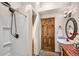 Bathroom featuring a stand up shower, vanity with vessel sink, decorative mirror, and natural wood door at 459 Virginia Ave, Palmer Lake, CO 80133