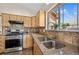 Well-lit kitchen with stainless steel appliances, granite countertops, tile backsplash, and a double basin sink beneath a window at 459 Virginia Ave, Palmer Lake, CO 80133