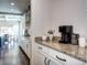 Kitchen featuring stainless steel appliances, white cabinets, granite counters, and bar with coffee maker at 15160 W Iliff Pl, Lakewood, CO 80228