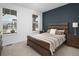 This staged bedroom features 2 light-filled windows, a dark accent wall, and neutral decor at 5128 Preserve Pl, Firestone, CO 80504