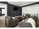 Cozy living room with ample seating, a dark accent wall and hardwood floors at 5128 Preserve Pl, Firestone, CO 80504
