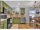 Bright eat-in kitchen featuring stainless steel appliances, green cabinets, and hardwood flooring at 165 Montgomery Dr, Erie, CO 80516