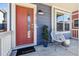 Inviting front porch with a chair, potted plant, and a vibrant red front door at 5760 N Boston St, Denver, CO 80238