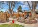 Landscaped backyard featuring a built-in fire pit, gazebo-covered hot tub, mature trees, and multiple seating areas at 6334 S Elati St, Littleton, CO 80120