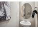 A powder room boasts a pedestal sink, oval mirror and elegant black and white artwork at 18379 Field Mint Pt, Parker, CO 80134