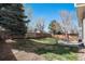 A well-maintained backyard with a grass lawn, mature trees, a stone patio, and an outdoor dining set at 5821 S Quatar Cir, Centennial, CO 80015
