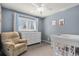 Bedroom with a cozy armchair, white dresser, and crib next to a window with natural light at 5821 S Quatar Cir, Centennial, CO 80015