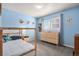 Light blue bedroom with a wooden bed, dresser, and window with natural lighting and grey curtains at 5821 S Quatar Cir, Centennial, CO 80015
