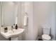 Clean powder room with a pedestal sink, round mirror, toilet, and tile flooring at 1919 W 46Th Ave # 3, Denver, CO 80211