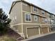 Exterior side angle view of a multi-story townhome with neutral siding and two garage doors at 553 Hanging Rock Pl, Castle Rock, CO 80108