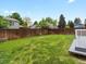 Large grassy backyard with a wood fence and a small deck, perfect for outdoor enjoyment and entertaining at 4858 S Quintero Cir, Aurora, CO 80015
