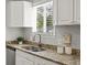 Kitchen sink beneath a window with granite countertops and white cabinets at 4858 S Quintero Cir, Aurora, CO 80015