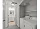 Bright laundry room with washer, dryer, and shelving next to bathroom at 4858 S Quintero Cir, Aurora, CO 80015