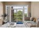 Living room featuring glass doors to balcony with beautiful green view at 6000 W Floyd Ave # 214, Denver, CO 80227